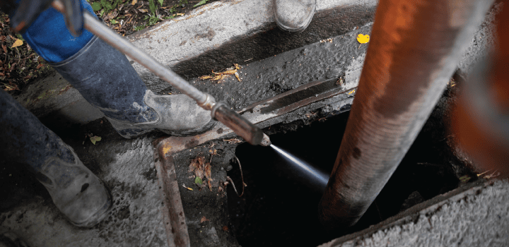 A professional drain technician uses a jetting hose to clear a gully drain in  Ashford.