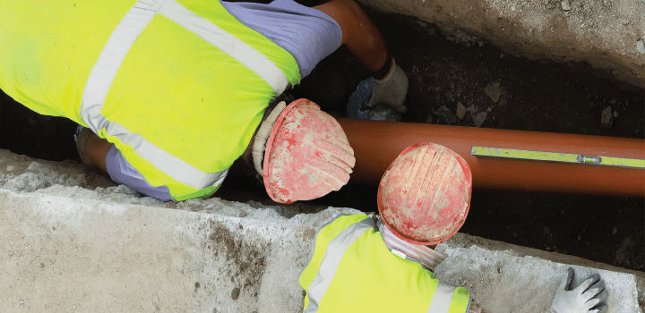 Two engineers in a trench fix a drain in Canterbury.