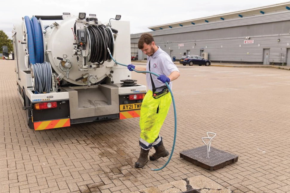 Chris pulls a hose from the water truck to unblock a drain in Sittingbourne