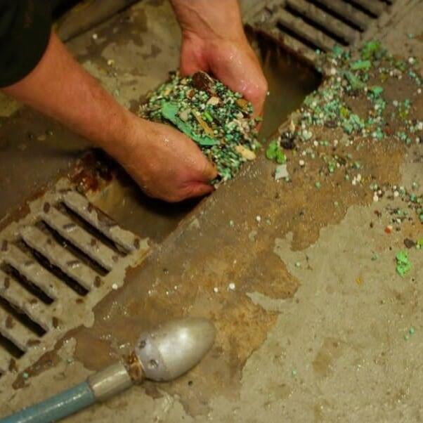 Large amounts of tiny plastic pieces taken out of a storm drain by hand.