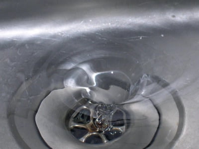 Clean water draining through a plug hole.