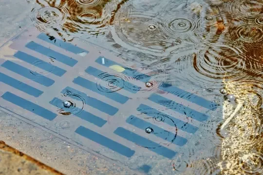 A storm drain overflowing with rain water.