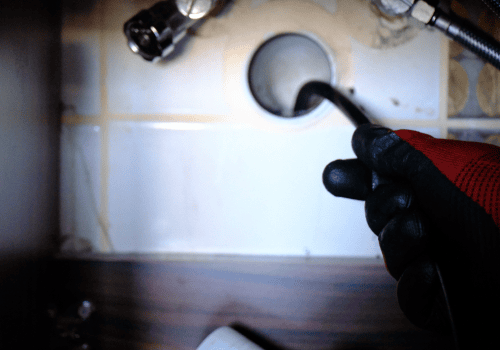 A flexible rod with a camera is inserted into a drain.