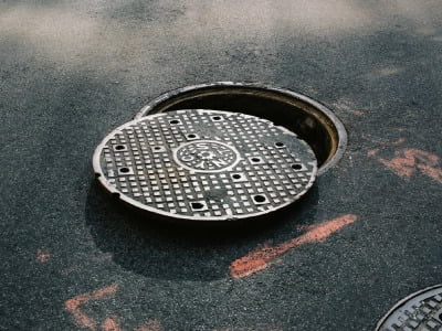 A manhole with its lid partially covering the opening.