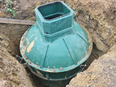 A septic tank submerged in a hole that has been dug in the ground.